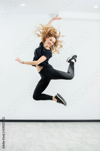 Fototapeta Naklejka Na Ścianę i Meble -  modern dance young beautiful dancer girl posing on studio background. Girl jumping in street dance style