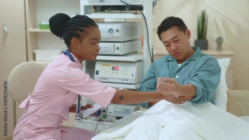 African american female physician doing professional checkup of chinese male client in private clinic hospital room asking disease symptoms giving recommendations. Communication. Consulting. African american female physician doing professional checkup of chinese male client in private clinic hospital room asking disease symptoms giving recommendations. Communication. Consulting.