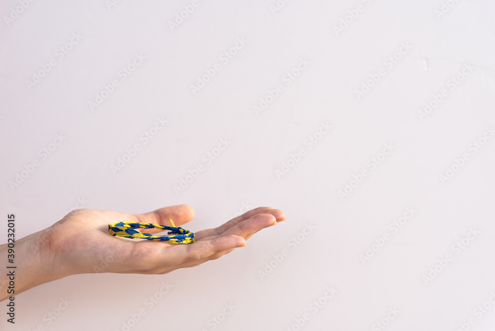 Fototapeta premium Wrist bracelet on woman's palm on the white background with copy space for text. Symbol of Ukraine on hand bracelet.with blue and yellow colors Dedication to culture of Ukraine