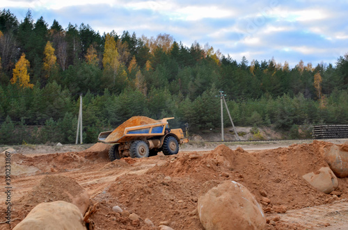 Earth mover loading dumper truck with sand in quarry. Excavator loading sand into dumper truck.Quarry for the extraction of minerals. Large quarry dump truck. Production useful minerals.