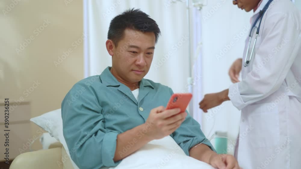 Asian handsome male patient sitting in the bed using smartphone searching medication instructions online talking with female nurse in hospital bed. Medicine concept. Asian handsome male patient sitting in the bed using smartphone searching medication instructions online talking with female nurse in hospital bed. Medicine concept.