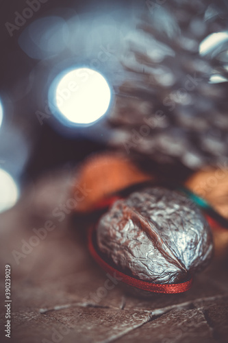 close-up of a painted silver nut with red and green ribbon on a dark background. christmas decoration with pine cone