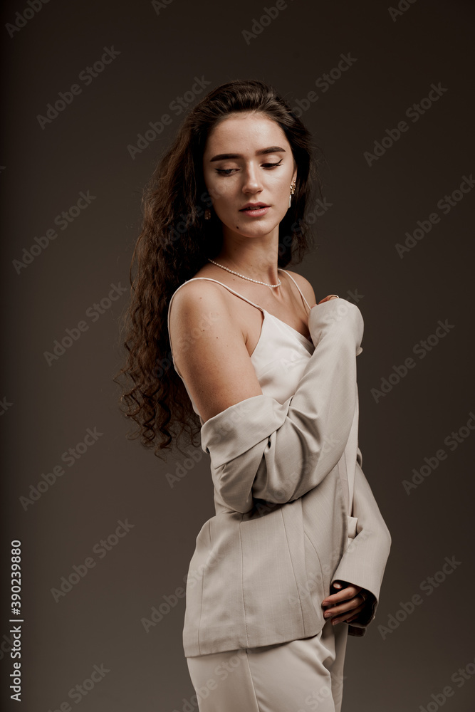 Fashion, elegant and sexy professional model in studio. Gorgeous young female in classic suit in photostudio. Attractive girl with curly hair posing for commercial photoshoot Fashion, elegant and sexy professional model in studio. Gorgeous young female in classic suit in photostudio. Attractive girl with curly hair posing for commercial photoshoot