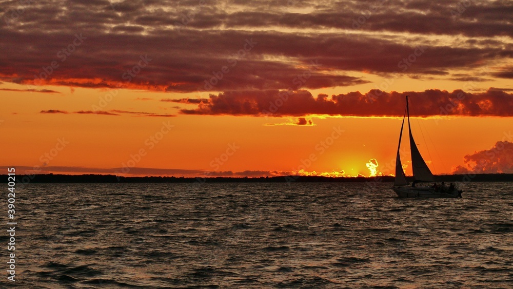 Sunset above Mazury lakes with a yacht sailing into the wind