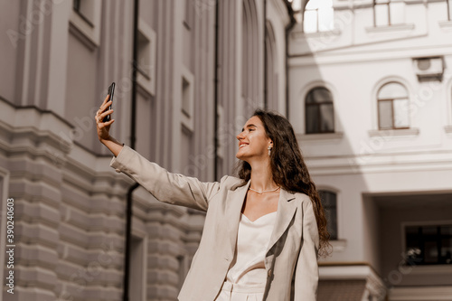 Attractive girl talking with her friends by video chats. On-line connection with family. Stay at home. Young business woman does selfie isolated in the city. © Rabizo Anatolii