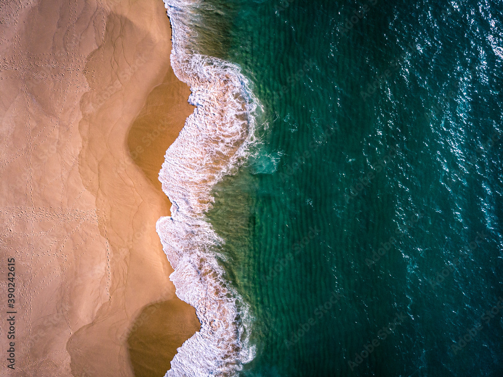 Aerial view of waves on a beautiful sandy ocean beach and cliff