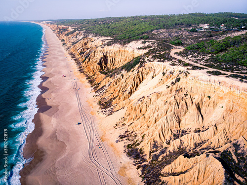 Aerial view of waves on a beautiful sandy ocean beach and cliff