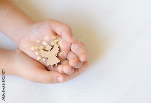 Wooden angel in children's hands on a white background, celebration, dream, Hope - Concept