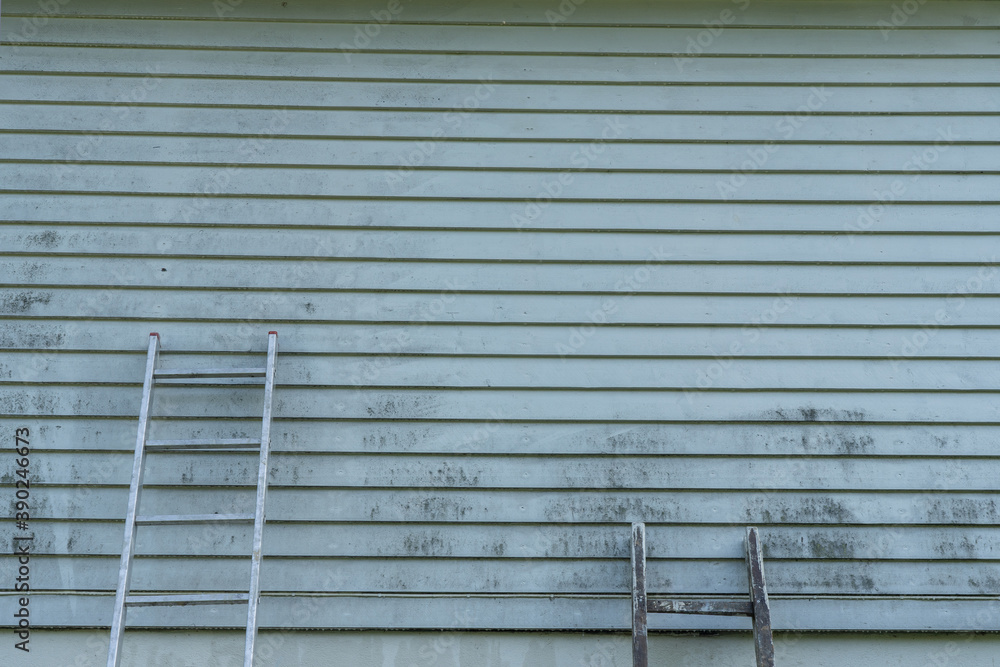 Ladders near light gray dirty wall. Ladders near light gray dirty wall.