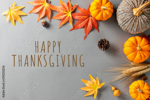 Happy Thanksgiving Day with maple leaves and pumpkin on grey background with text.