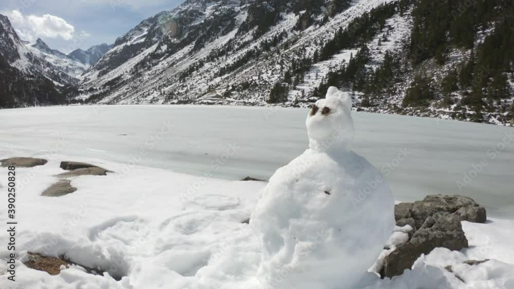 A cute little snowman near the frozen Gaube Lake (Lac de Gaube) in the French Pyrenees, in the department of the Hautes-Pyrénées, near the town of Cauterets, France. The Mount Vignemale in the back. A cute little snowman near the frozen Gaube Lake (Lac de Gaube) in the French Pyrenees, in the department of the Hautes-Pyrénées, near the town of Cauterets, France. The Mount Vignemale in the back.