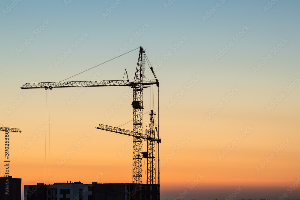 Two lifting crane at sunset