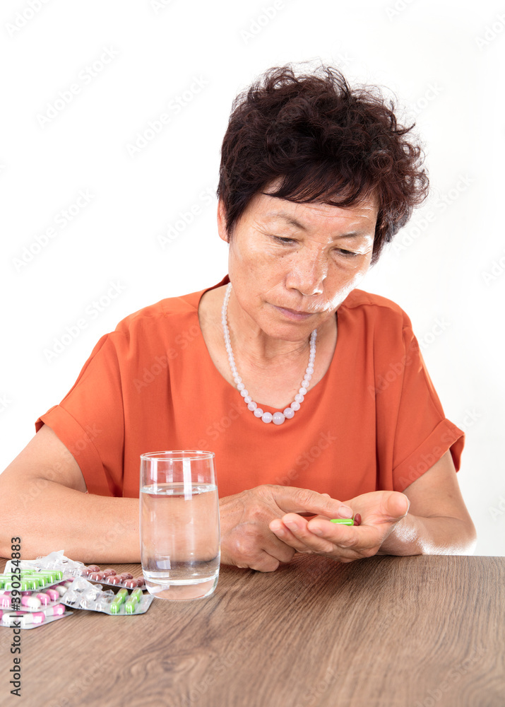 The old Chinese lady in front of a white background is about to take medicine to treat the disease
