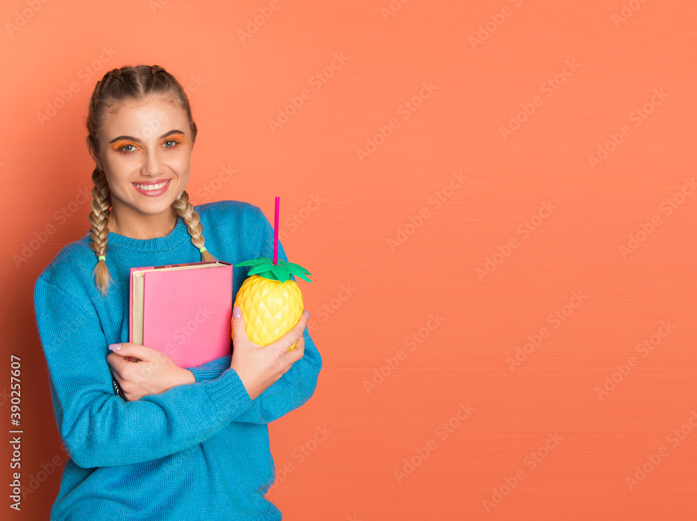 Teenage school girl holding notebook smiling on orange background with copy space horizontal Teenage school girl holding notebook smiling on orange background with copy space horizontal