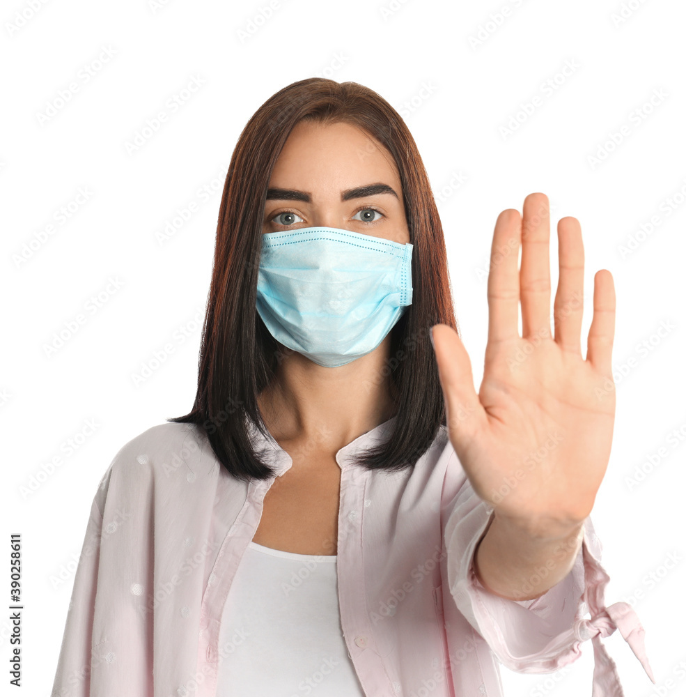 Young woman in protective mask showing stop gesture on white background. Prevent spreading of coronavirus Young woman in protective mask showing stop gesture on white background. Prevent spreading of coronavirus