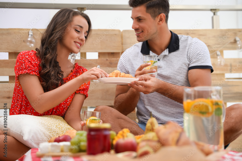 Happy couple with tasty food and drinks imitating picnic at home Happy couple with tasty food and drinks imitating picnic at home