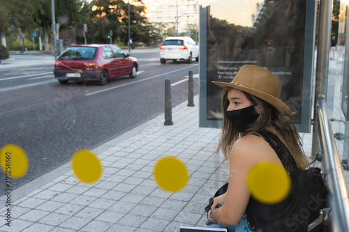 Closeup shot of a young girl waiting at a bus stop wearing a sanitary mask - the new normal photo