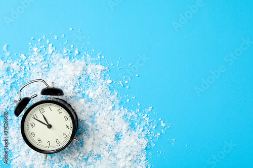 Alarm clock and snow on light blue background, flat lay with space for text. New Year countdown