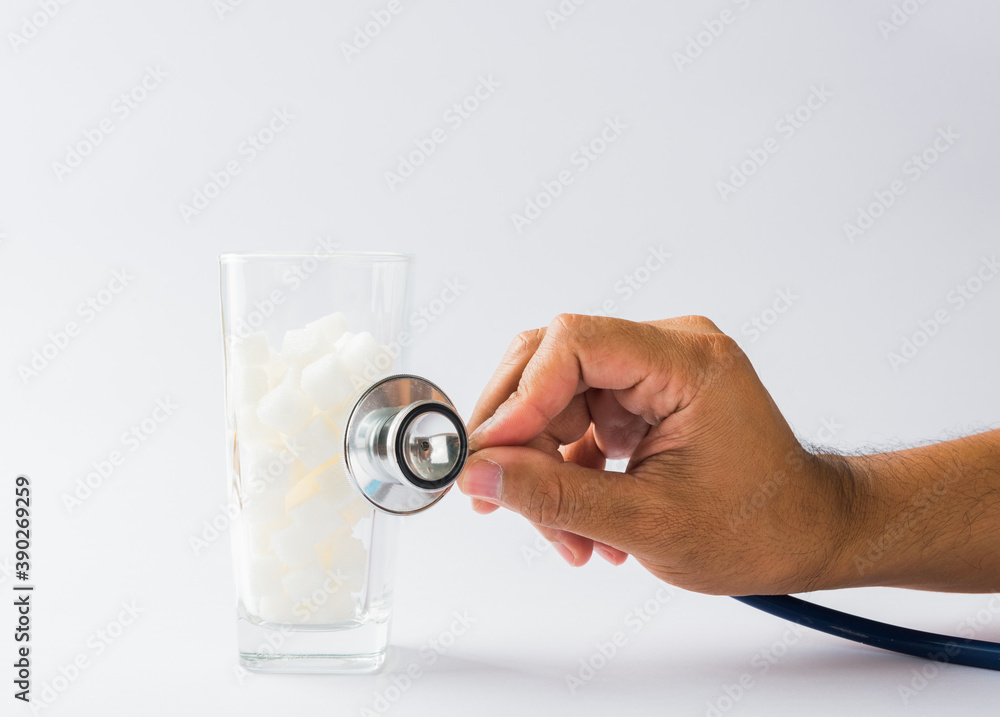 Hand of doctor hold stethoscope check on glass full of white sugar cube sweet food ingredient, isolated on white background, health high blood risk of diabetes and calorie intake unhealthy drink Hand of doctor hold stethoscope check on glass full of white sugar cube sweet food ingredient, isolated on white background, health high blood risk of diabetes and calorie intake unhealthy drink