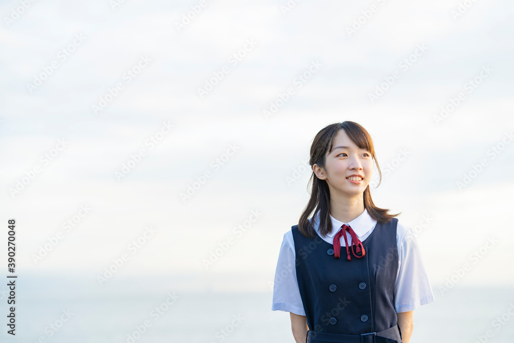 海を背景に、笑顔を見せる女子高生