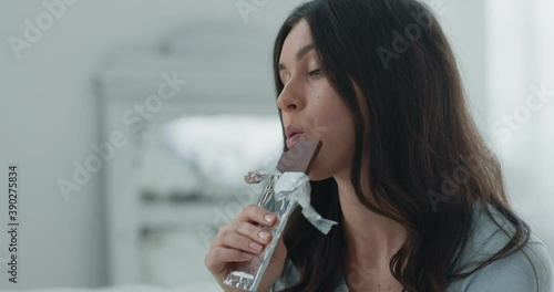 Seizing stress. Close up portrait of young depressed woman eating chocolate bar slow motion