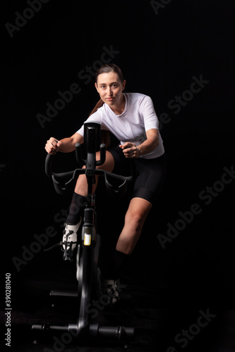 Smiling fitness girl racing on indoor exercise bike, front facing shot © The Branding Lab