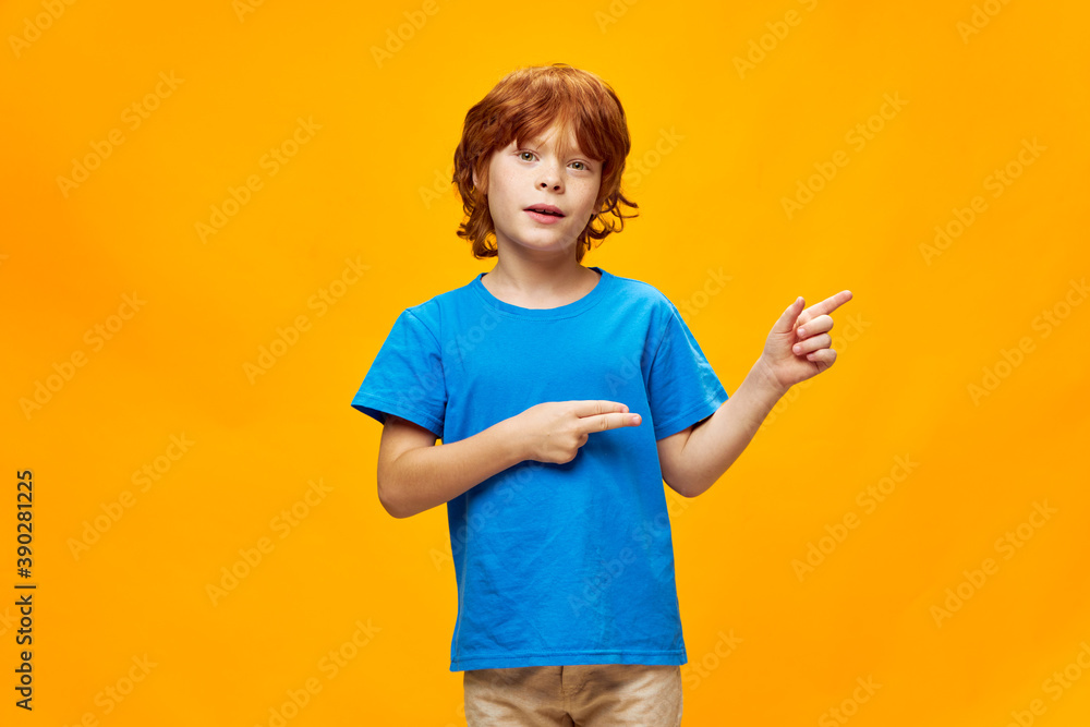 Red-haired boy showing thumbs to the side blue t-shirt lifestyle Copy Space Red-haired boy showing thumbs to the side blue t-shirt lifestyle Copy Space