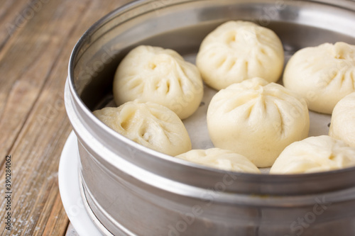 A closeup view of a steel steamer of Chinese baozi, in a restaurant or kitchen setting.