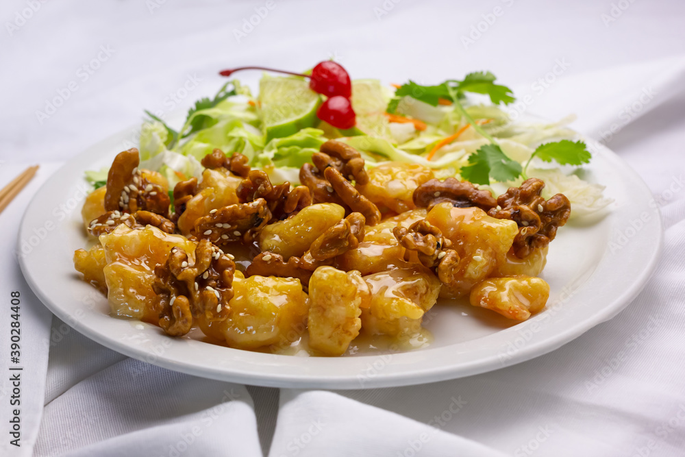 A view of a plate of honey walnut shrimp, in a restaurant or kitchen setting.