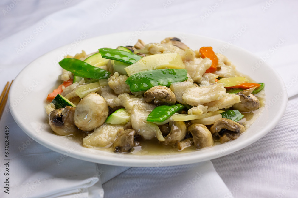 A view of a plate of mushroom chicken, in a restaurant or kitchen setting.