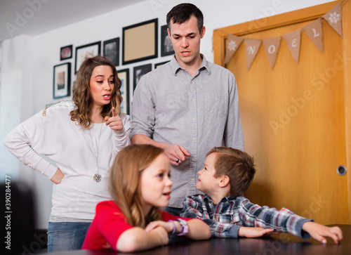 Young angry parents lecturing their children for bad behavior at home