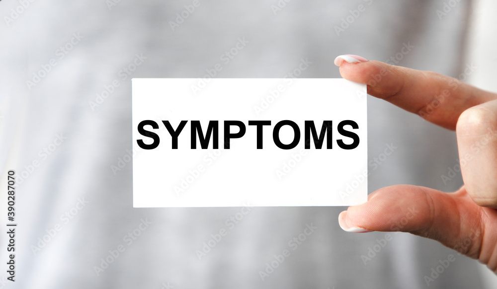 The girl holds a card with the text symptoms. A medical concept. The girl holds a card with the text symptoms. A medical concept.