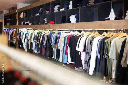 Men clothing shop, assorted casual clothes on hangers and shelves in apparel store