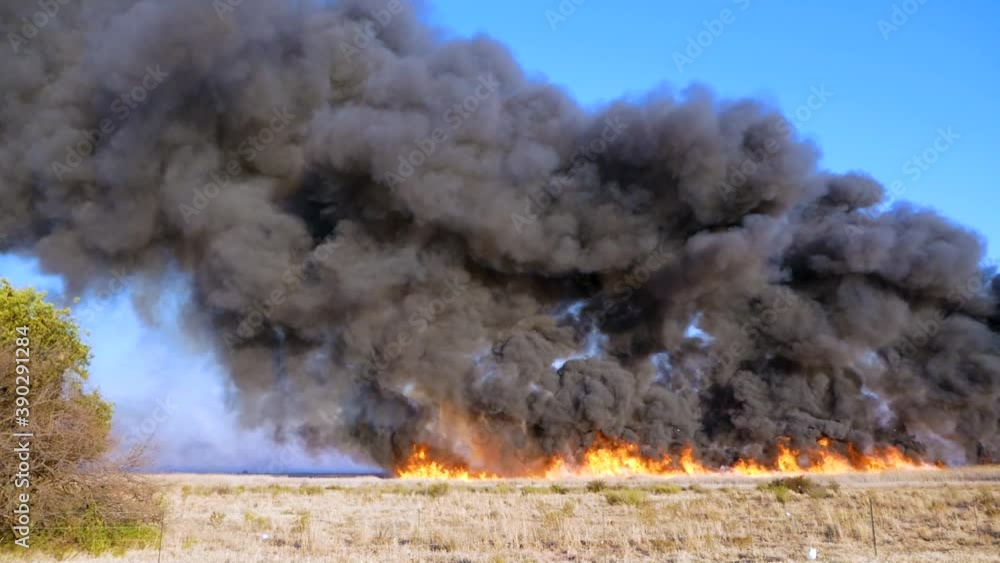 Field on fire with big flames and dark smoke Field on fire with big flames and dark smoke