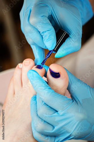 Process pedicure close up. Unrecognizable people. Master chiropody applying gel nail polish. Spa. Concept body care.
