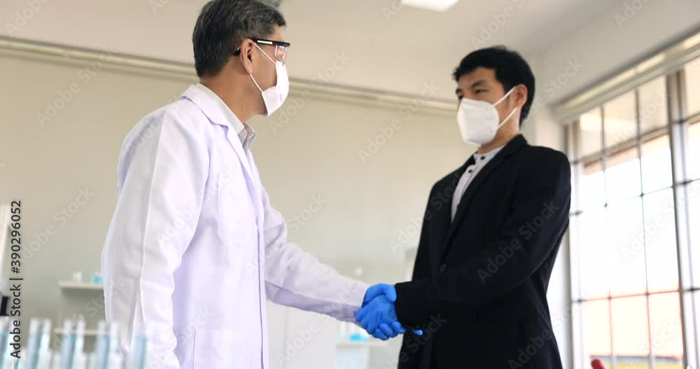 Asian doctor and businessman holding the COVID vaccine on laboratory after test on human success and have agreed to buy and sell. Asian doctor and businessman holding the COVID vaccine on laboratory after test on human success and have agreed to buy and sell.
