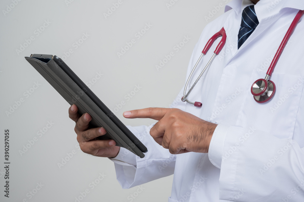 Close Up Doctor in white coat, stethoscope holding tablet and pointing look.into camera isolated on white background.