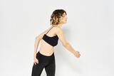 Slender woman in leggings on a light background doing fitness gymnastics exercises