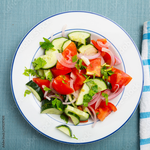 Vegetable salad with fresh tomatoes, cucumbers, sliced onion and olive oil
