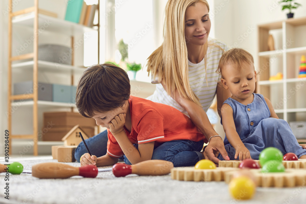 Obraz premium Mother and children playing and drawing at home together