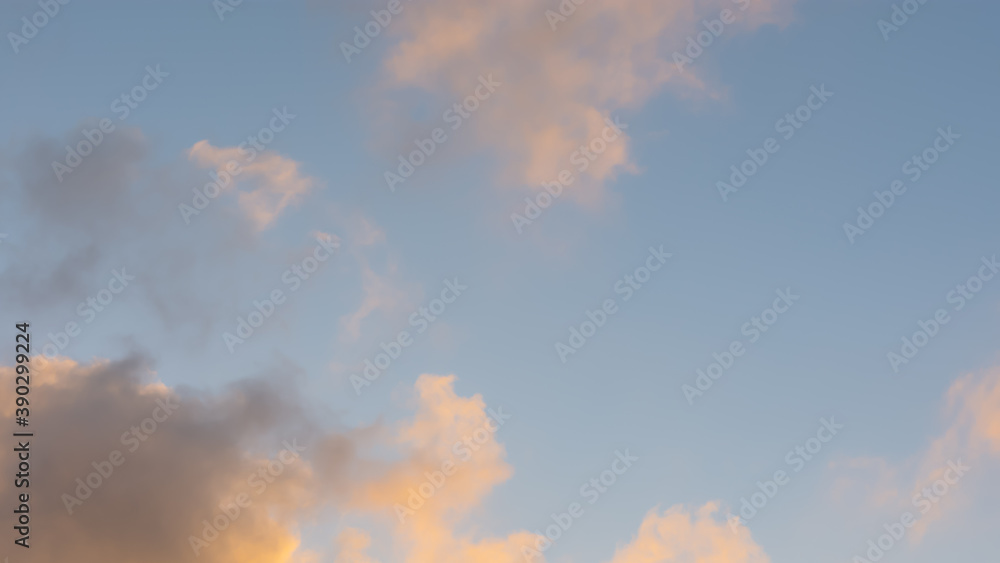 Full frame of sunset orange clouds in a blue sky. The concept of changing the weather. Abstract natural background. A bright natural phenomenon. Fluffy gray clouds. Full frame with copy space