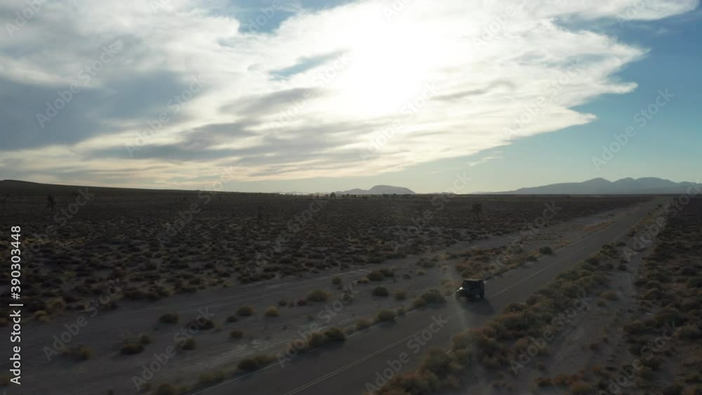 Jeep driving down a Mojave Desert road at sunset - aerial view on a summer day Jeep driving down a Mojave Desert road at sunset - aerial view on a summer day