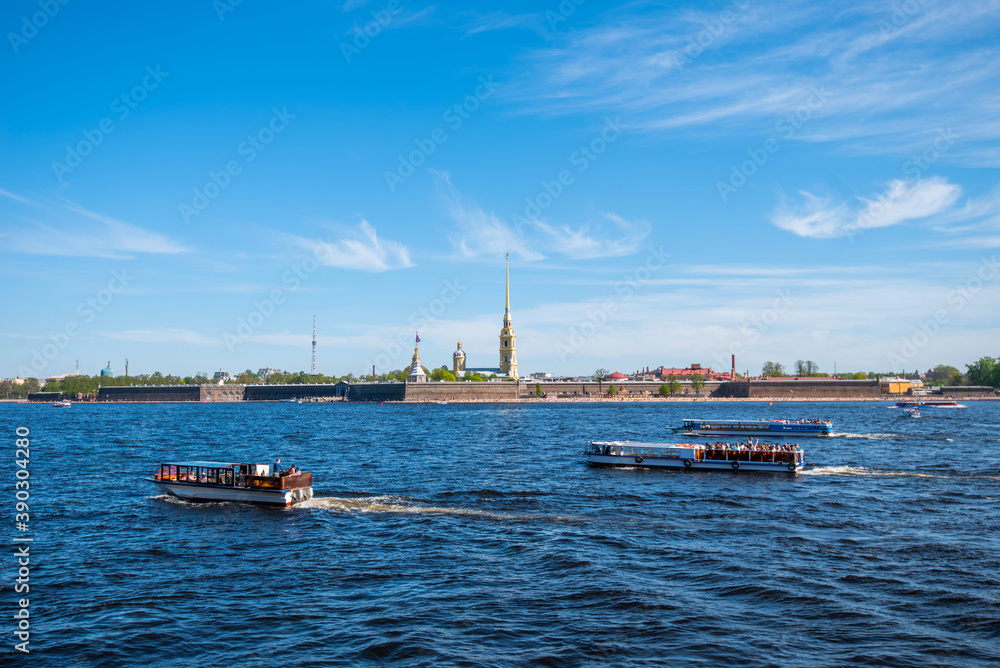 Small tourist ships sail on the Neva River in Saint Petersburg in summer. Peter and Paul fortress. Petersburg architecture. Petersburg museums. Walls of fortress, blue sky, landscape, sunny day.