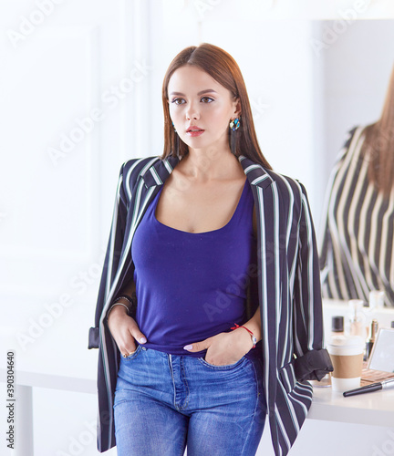 Amazing young woman doing her makeup in front of mirror. Portra