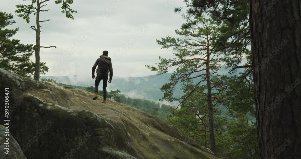 A man is climbing a cliff. He is standing and looking at nature. Hiking in the mountains. 4K DCI A man is climbing a cliff. He is standing and looking at nature. Hiking in the mountains. 4K DCI