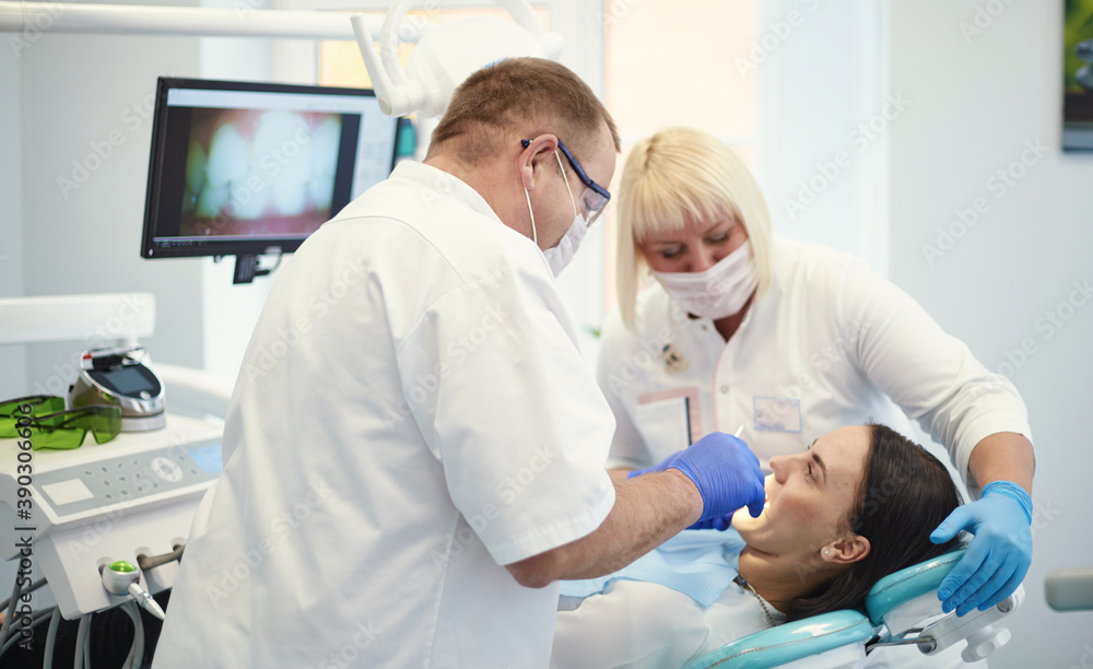 Doctor dentist treats teeth of a beautiful young girl patient. The girl on reception at the dentist. Doctor dentist treats tooth Doctor dentist treats teeth of a beautiful young girl patient. The girl on reception at the dentist. Doctor dentist treats tooth