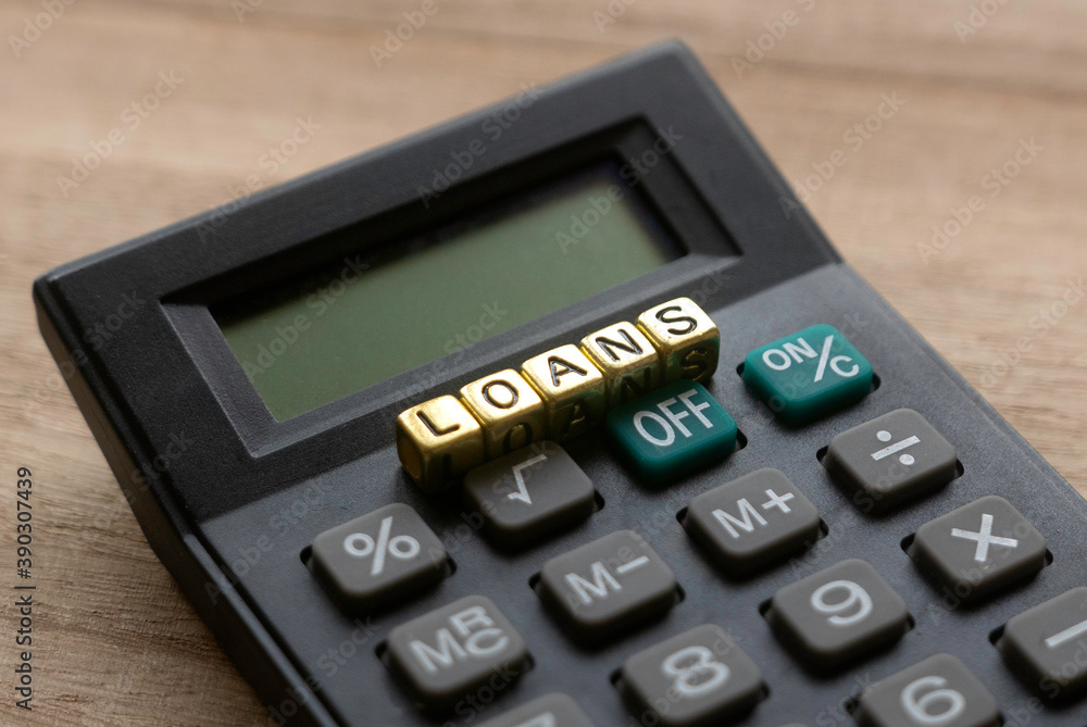 Selective focus of calculator and gold alphabet beads of word Loans on wooden background. Selective focus of calculator and gold alphabet beads of word Loans on wooden background.