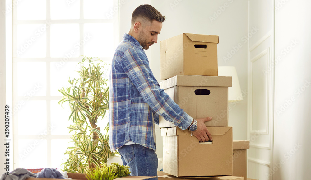 Handsome man with boxes in the new apartment after moving Handsome man with boxes in the new apartment after moving