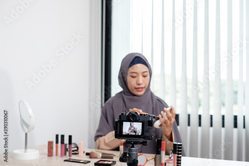 Muslim women making video beauty vlogger bloggers doing a cosmetic makeup tutorial vlog with brushes looking camera Save clips and share them on social media live via the internet Online