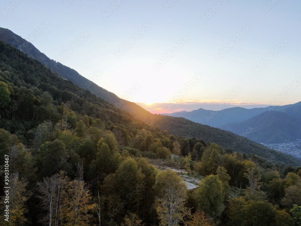 Aerial view panorama of sunset between mountains against the background of a blue sky. Beautiful sunset landscape in the mountains